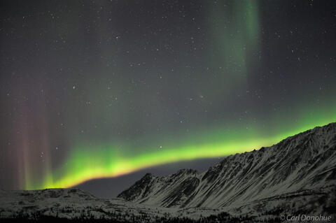 The northern lights start to light up the nighttime sky in interior Alaska, over the magnificent Alaska Range.