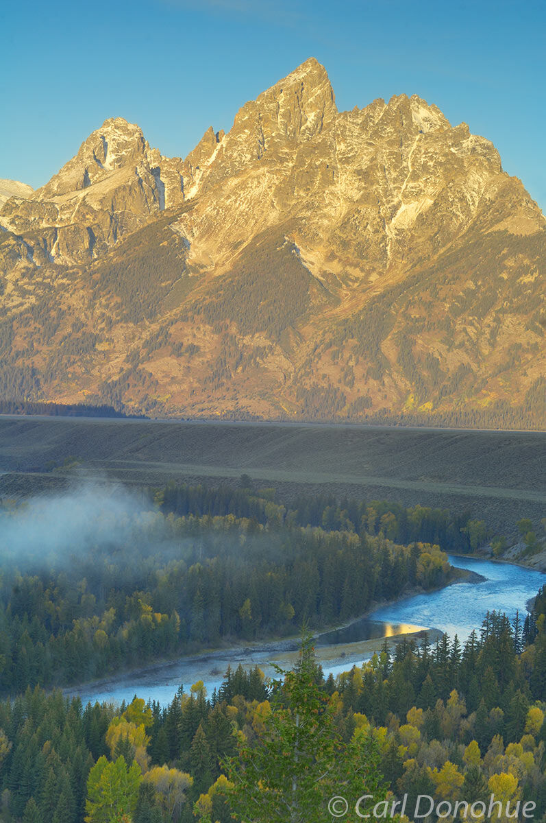 Dawn rises over the Grand Teton mountain range, and fall colors on the Snake River. Photo taken from Snake River Overlook, in...