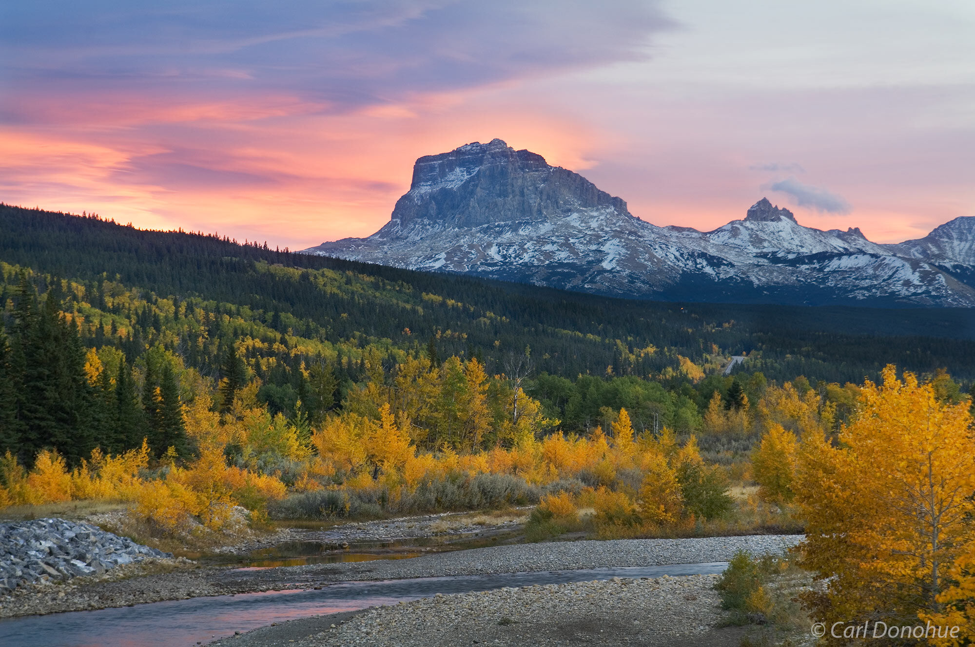 Sunset above Chief Mountain, sentinel of the Canadian Rockies, and the vibrant colors of fall in the forest, Waterton Lakes National...