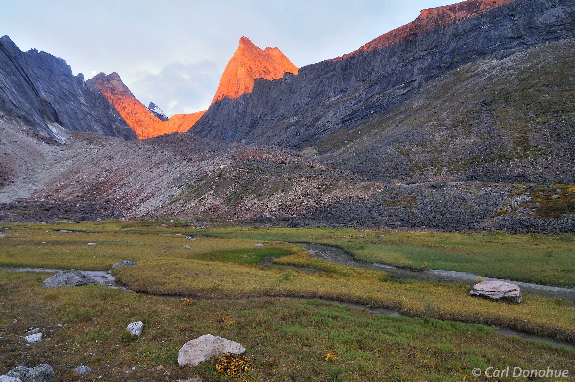 Sunrise catches the peaks of The Maidens, and Elephant’s Tooth in the background, in Alaska’s Arrigetch Peaks. The Arigetch...