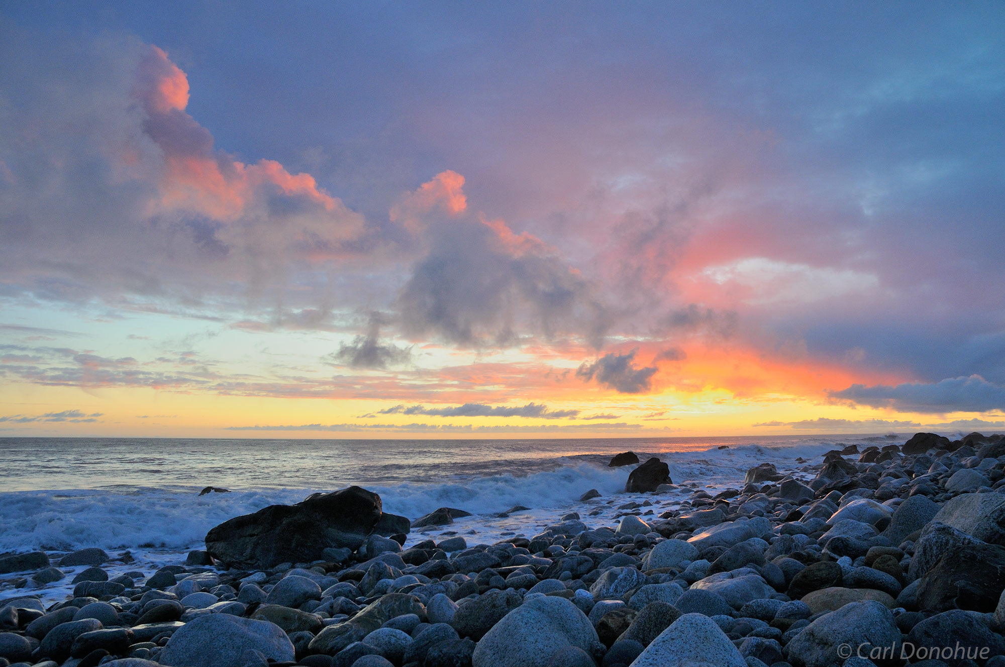 A colorful sunset at Sitkagi Lagoon. Rocks and boulders strewn along the beach of Sitkagi Bluffs, near the Malaspina Glacier....