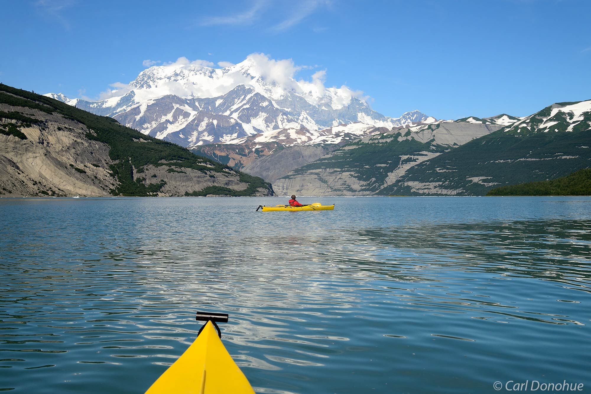 A photo of a young man sea kayaking in Icy Bay under the towering Mt. St. Elias. Paddling under the world's highest coastal mountain...