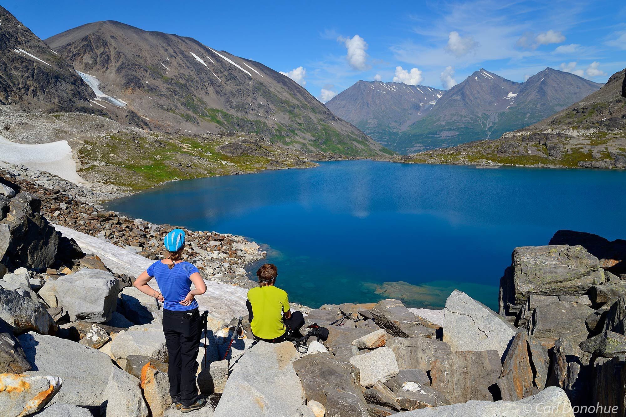Hikers in the Wrangell - St. Elias National Park backcountry take a break and stop to admire the view of a beautiful little alpine...