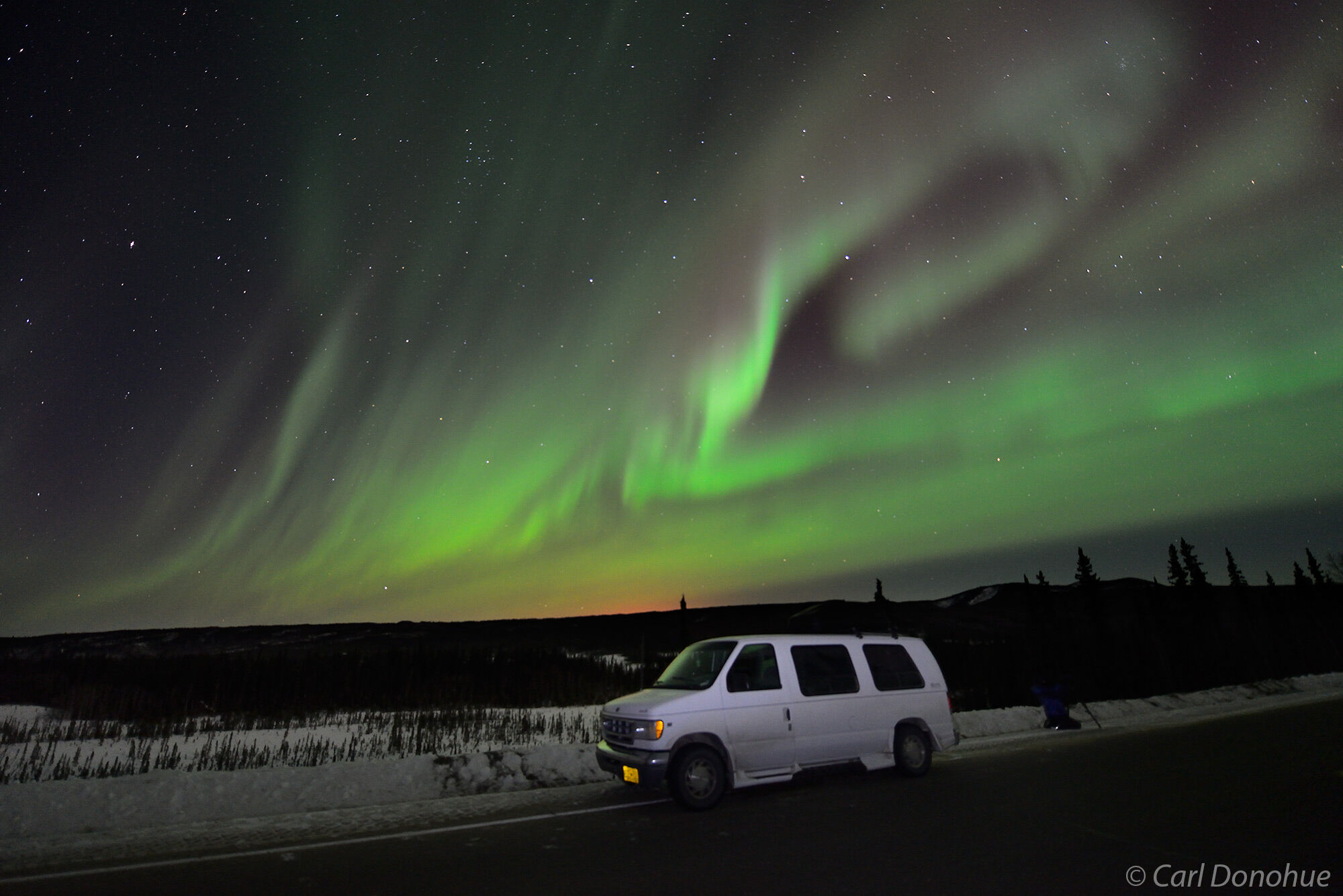 The aurora borealis over a Ford van used for photo tours on the Elliot highway, in subarctic Alaska.