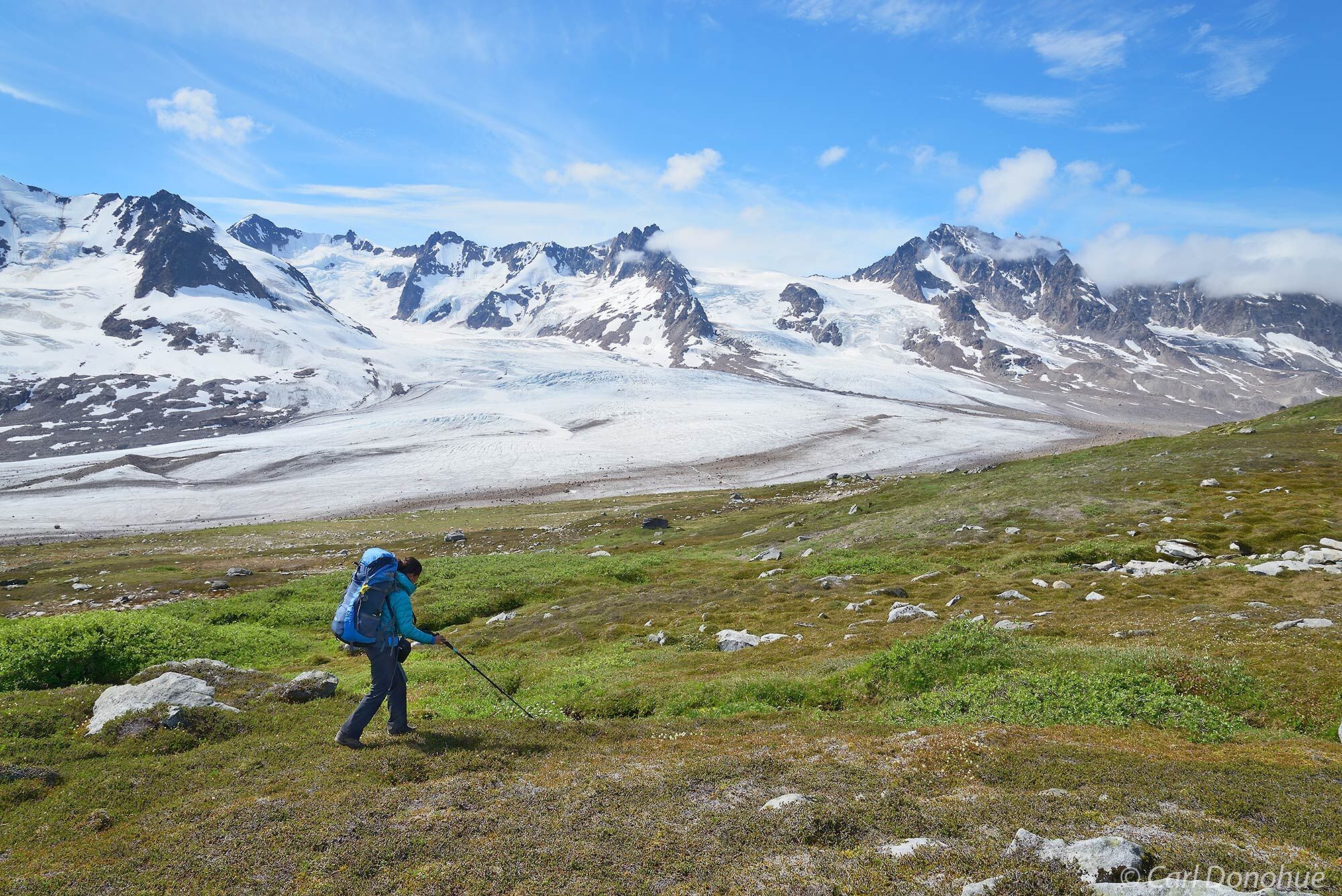 A woman of color backpacking down a mountain toward a glacier on the 7 Pass Route, Wrangell - St. Elias National Park, Alaska...
