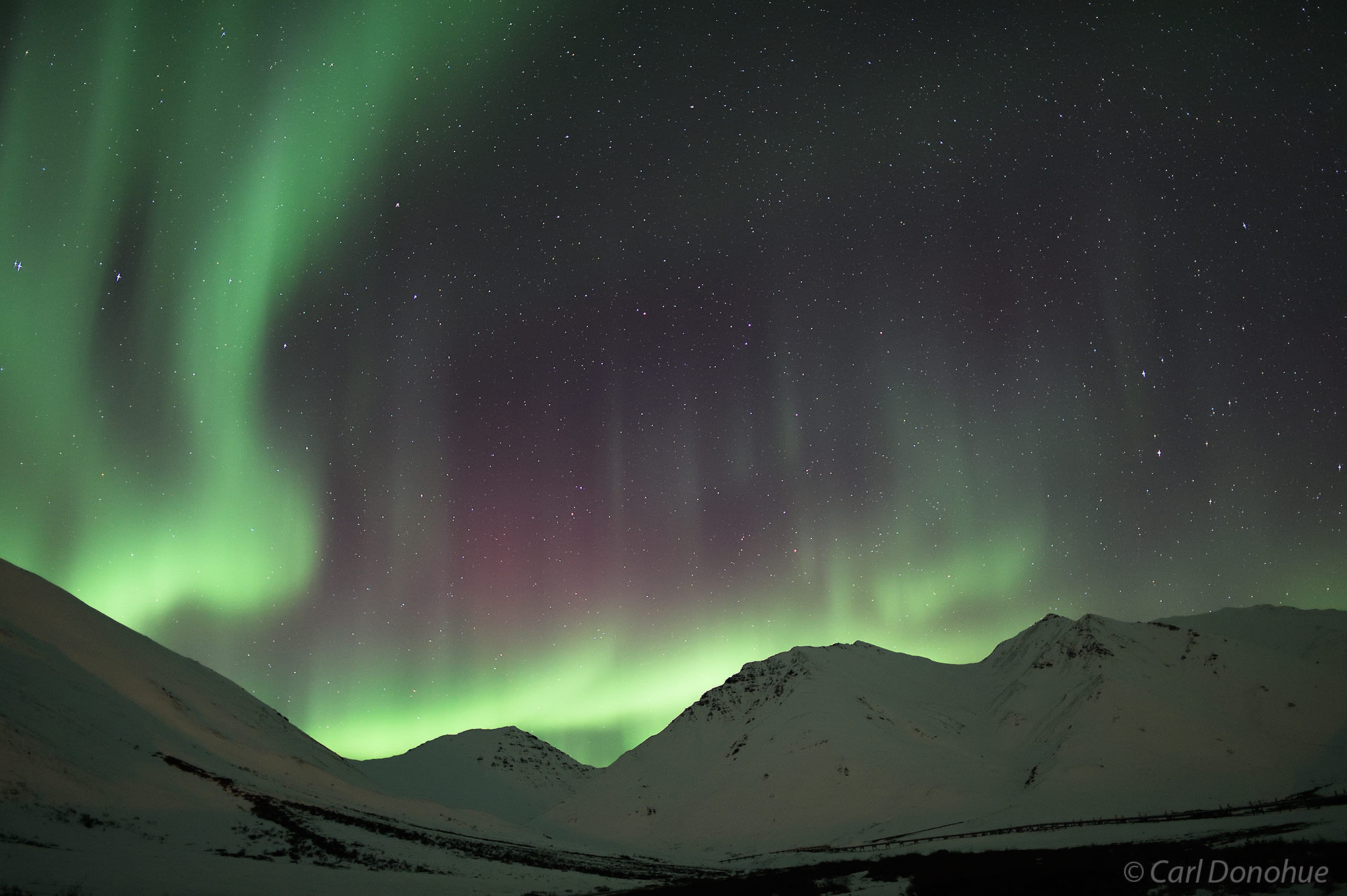 In Arctic Alaska near Atigun Pass the aurora borealis stretches across the sky over the Brooks Mountain Range. This photo was...