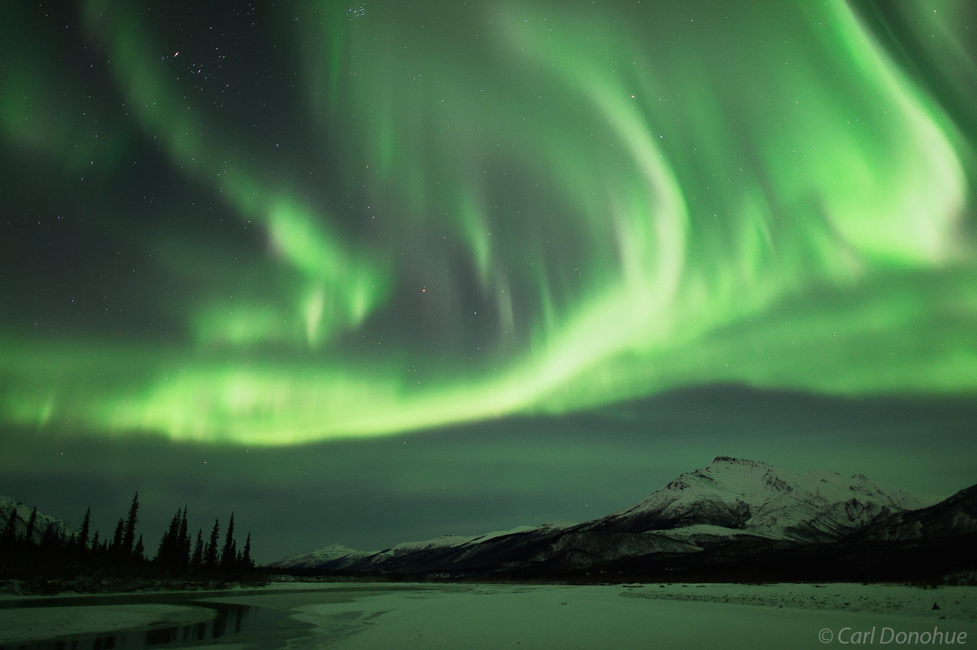 A tremendous Aurora borealis or northern lights display, reaches across the sky above the Brooks Range and Gates of the Arctic...